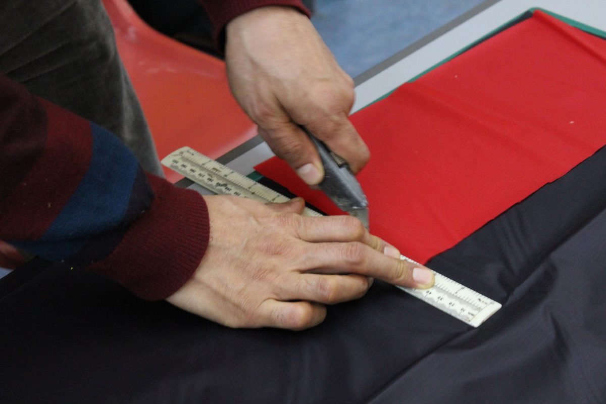 Close up of Ahmadzia's hands as he cuts a piece of the kite material