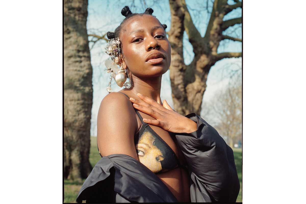 A woman holds her hand to her chest as she looks at the camera