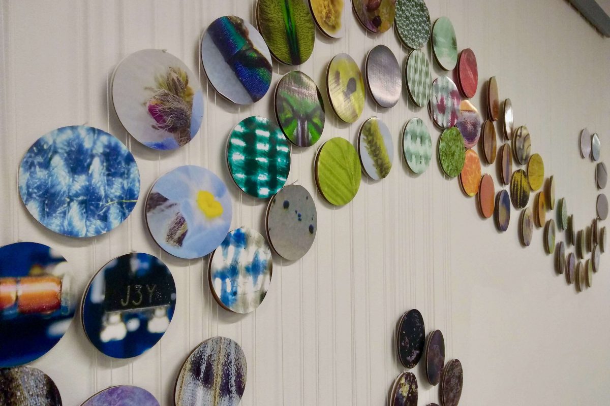 Close up of many small round photos arranged in a swirl shape on a wall