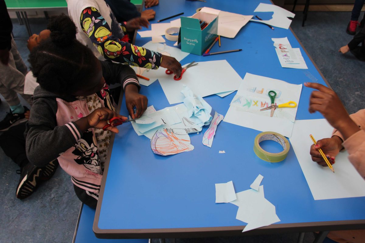 Children cutting and sticking colourful paper at a table